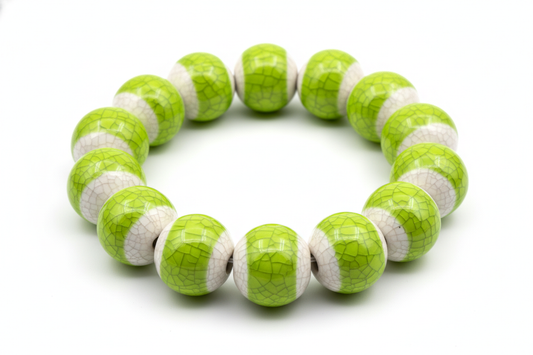 a beaded porcelain bracelet with ice crackled glaze in bright green on top of each bead on a white background