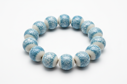 A porcelain beaded bracelets with an ice-crackled glaze in Azure Mist on top of each bead on a white background
