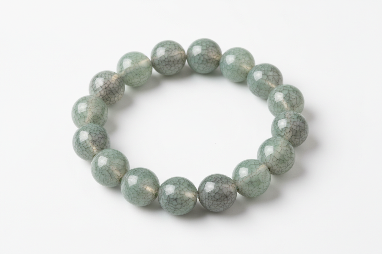 A porcelain beaded bracelets with an ice-crackled glaze in Jade Smoke on top of each bead on a white background