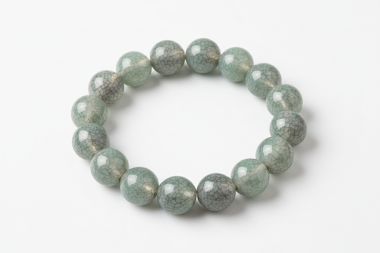 A porcelain beaded bracelets with an ice-crackled glaze in Jade Smoke on top of each bead on a white background