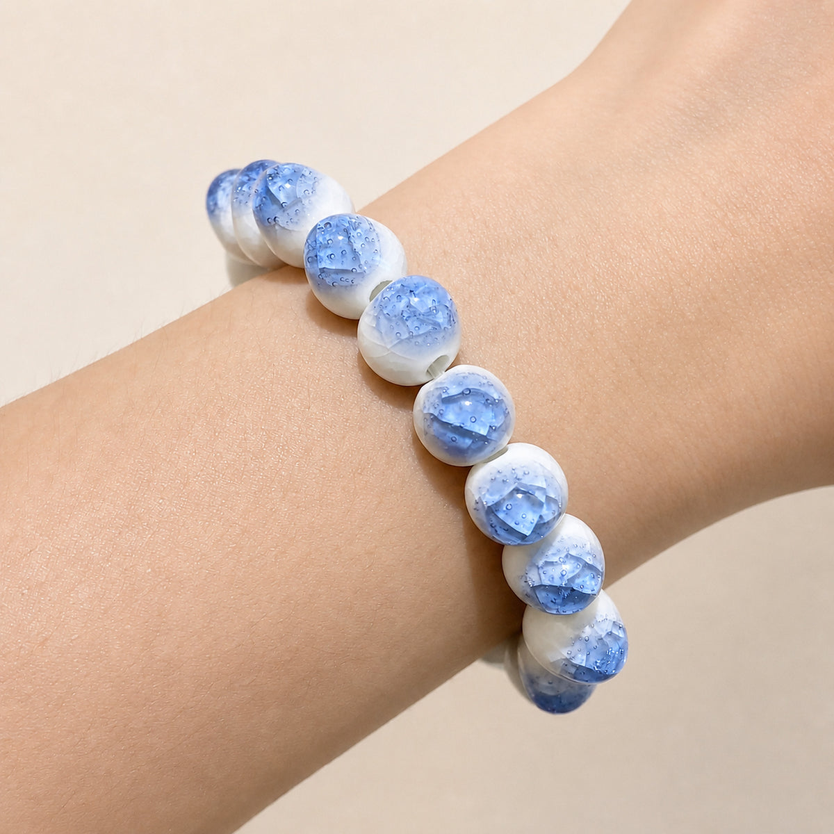 LUMI blue ice-crackle glaze ceramic bracelet 10mm worn on the wrist — handmade Jingdezhen porcelain, wrist shot 1