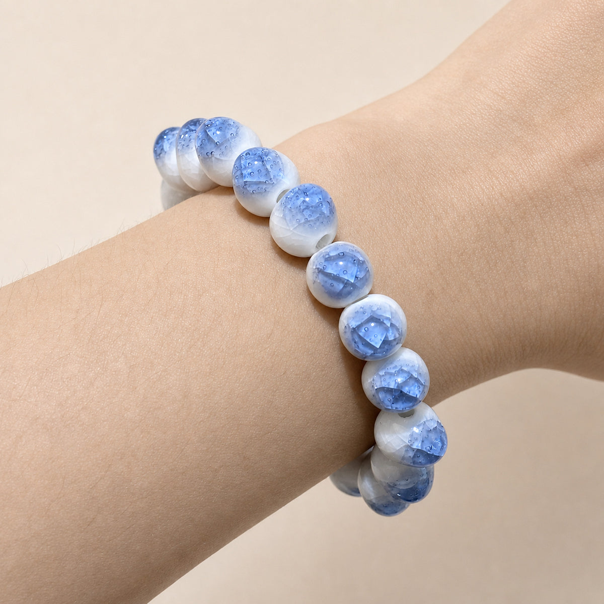 LUMI blue ice-crackle glaze ceramic bracelet 10mm worn on the wrist — handmade Jingdezhen porcelain, wrist shot 4