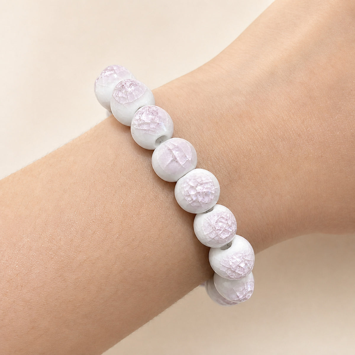 LUMI pink ice-crackle glaze ceramic bracelet 10mm worn on the wrist — handmade Jingdezhen porcelain, wrist shot 1