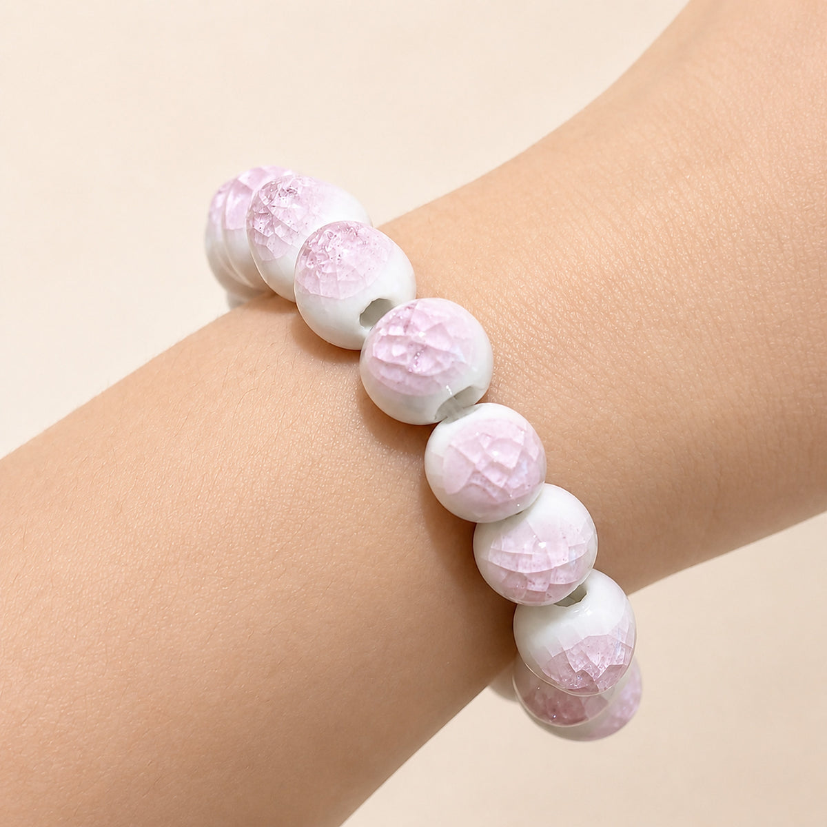 LUMI pink ice-crackle glaze ceramic bracelet 10mm worn on the wrist — handmade Jingdezhen porcelain, wrist shot 2