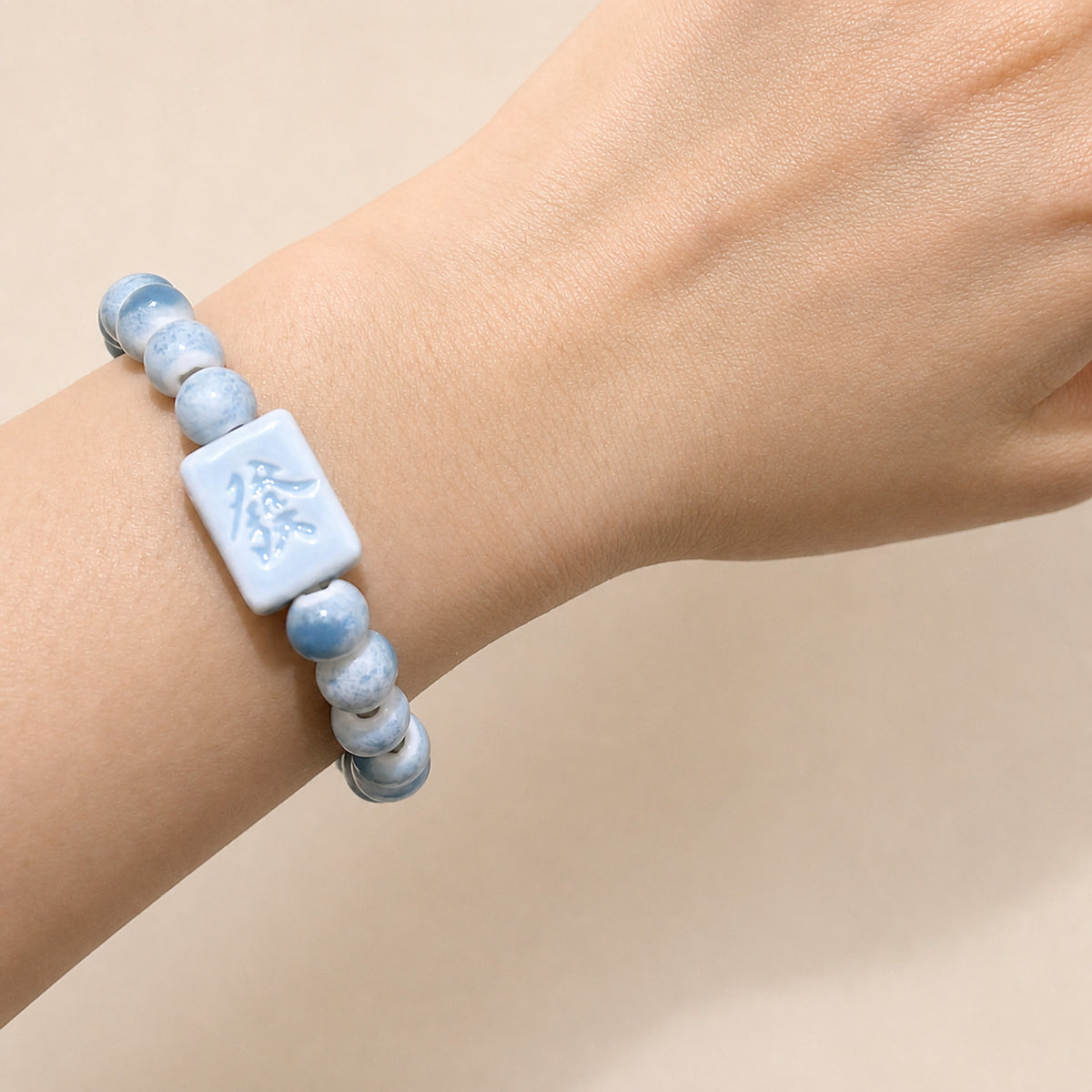 LUMI blue 發 fortune character ceramic bracelet 8mm worn on the wrist — handmade Jingdezhen porcelain, wrist shot 1