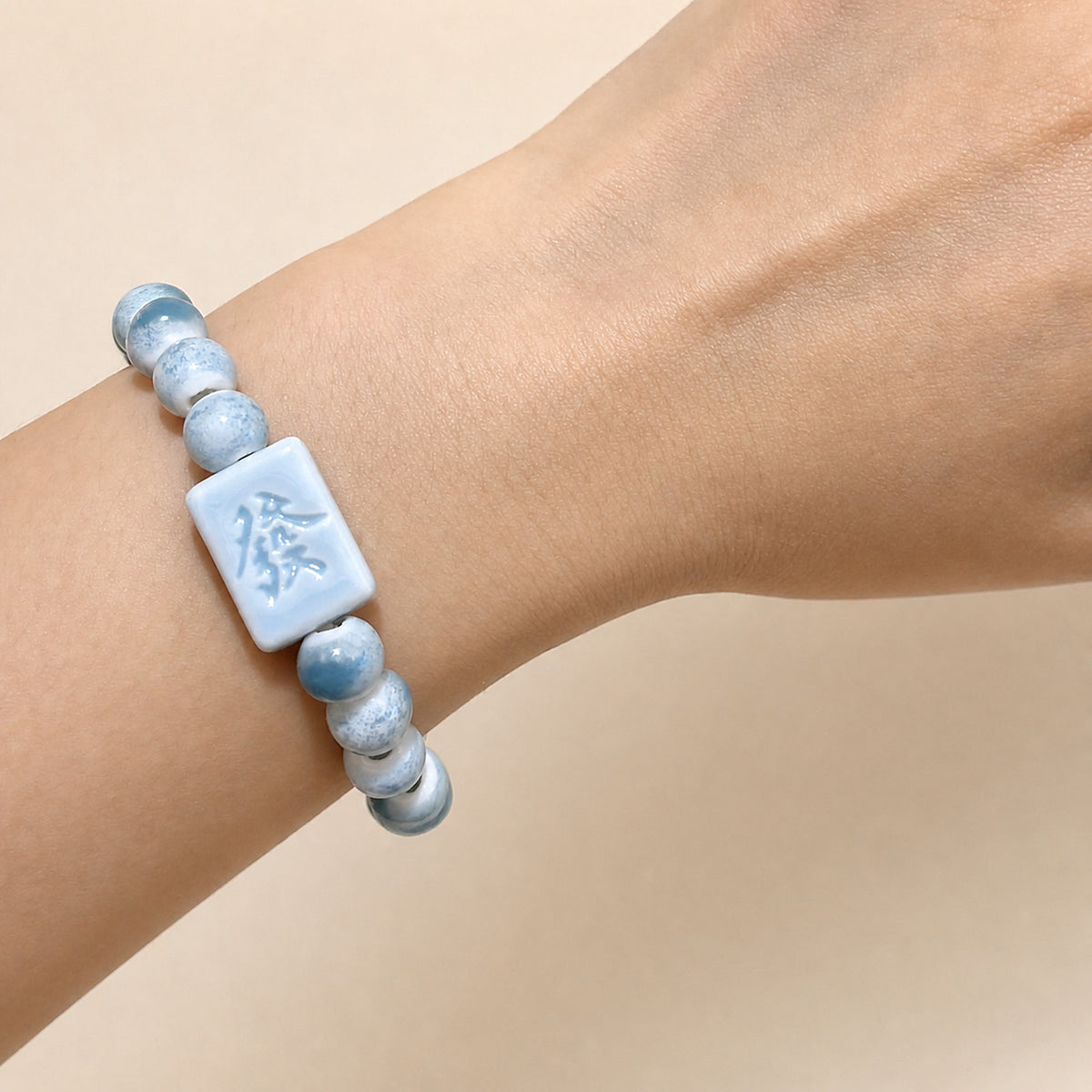 LUMI blue 發 fortune character ceramic bracelet 8mm worn on the wrist — handmade Jingdezhen porcelain, wrist shot 2