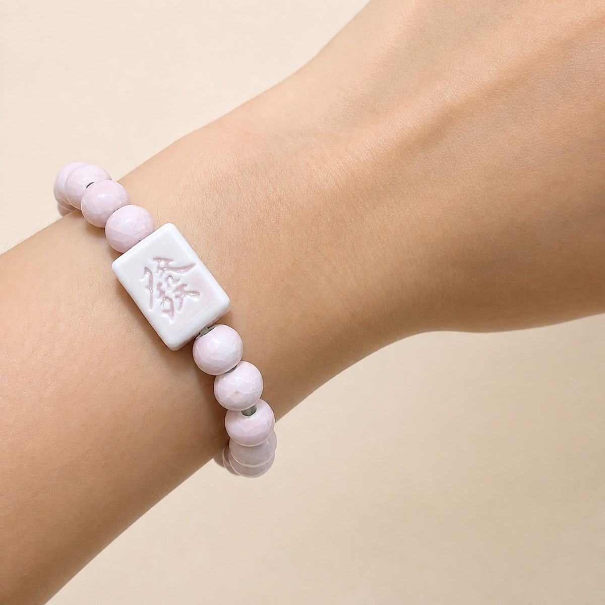 LUMI pink 發 fortune character ceramic bracelet 8mm worn on the wrist — handmade Jingdezhen porcelain, wrist shot 1