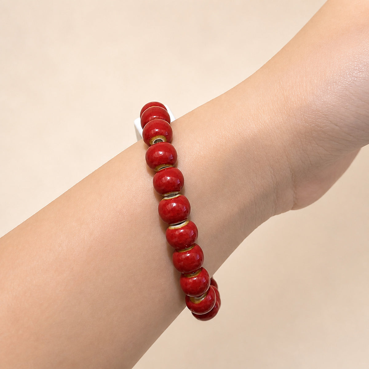 LUMI red 發 fortune character ceramic bracelet 8mm worn on the wrist — handmade Jingdezhen porcelain, wrist shot 2