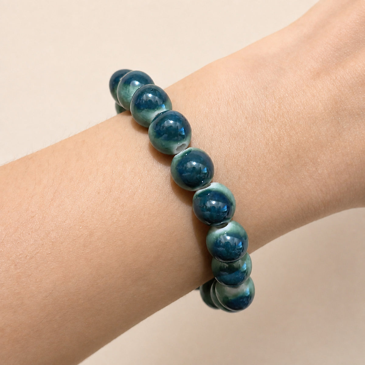 LUMI forest green ceramic bracelet 10mm worn on the wrist — handmade Jingdezhen porcelain, wrist shot 1