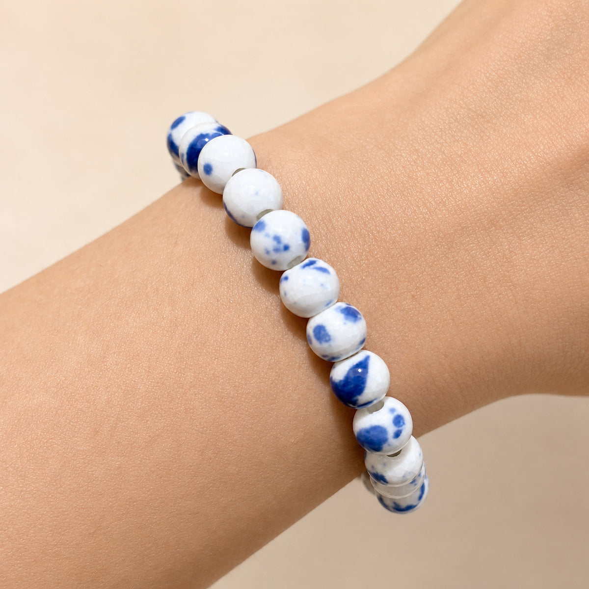 LUMI Qing Hua blue-and-white porcelain bracelet 8mm worn on the wrist — handmade Jingdezhen porcelain, wrist shot 1