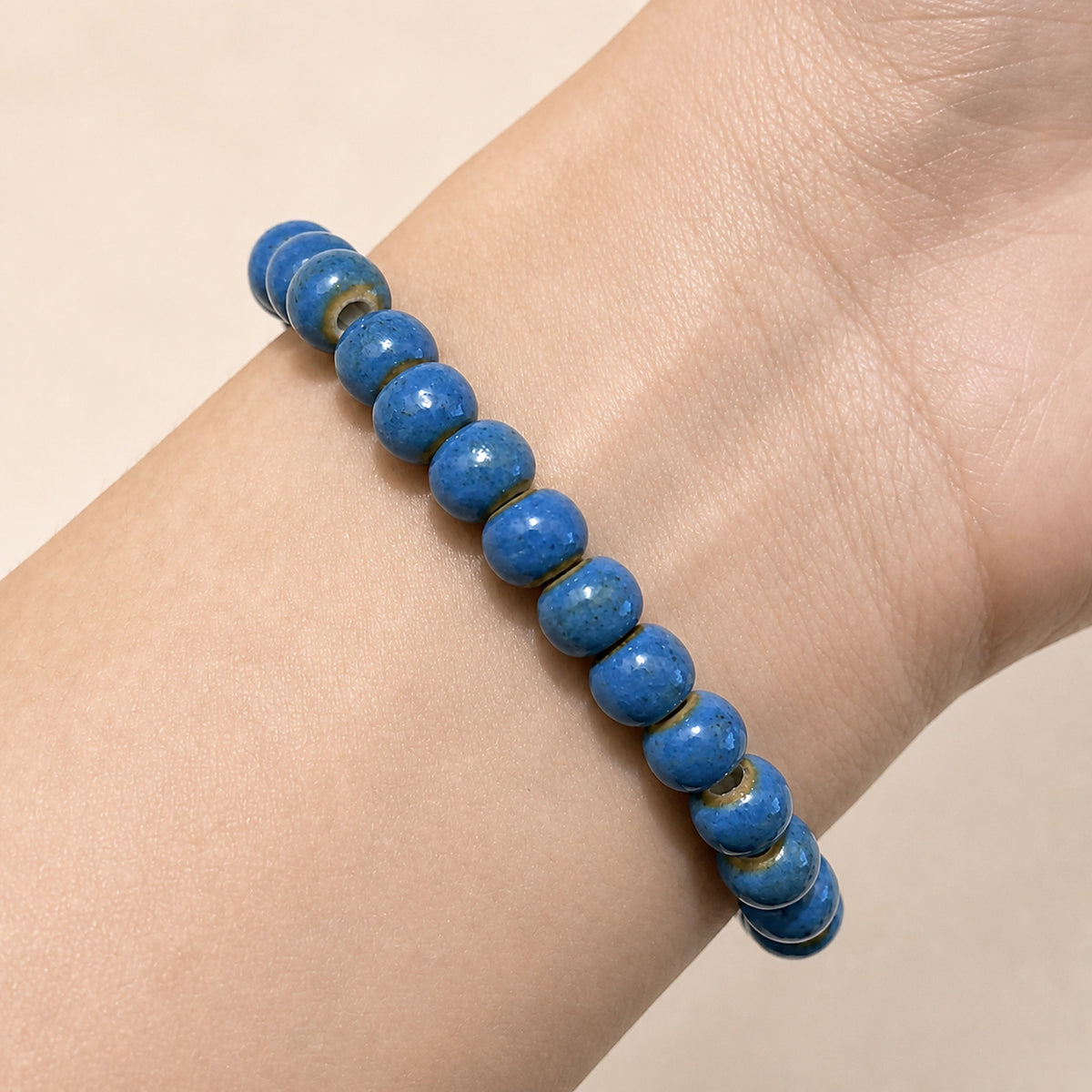 LUMI cobalt blue ceramic bracelet 6mm worn on the wrist — handmade Jingdezhen porcelain, wrist shot 1